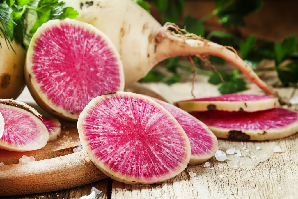 Slices of pink watermelon radish on a wooden table with parsley by 5PH on 500px.com