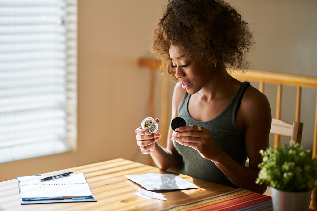 woman at home looking at container of marijuana bought from legal dispensary by Joshua Resnick on 500px.com