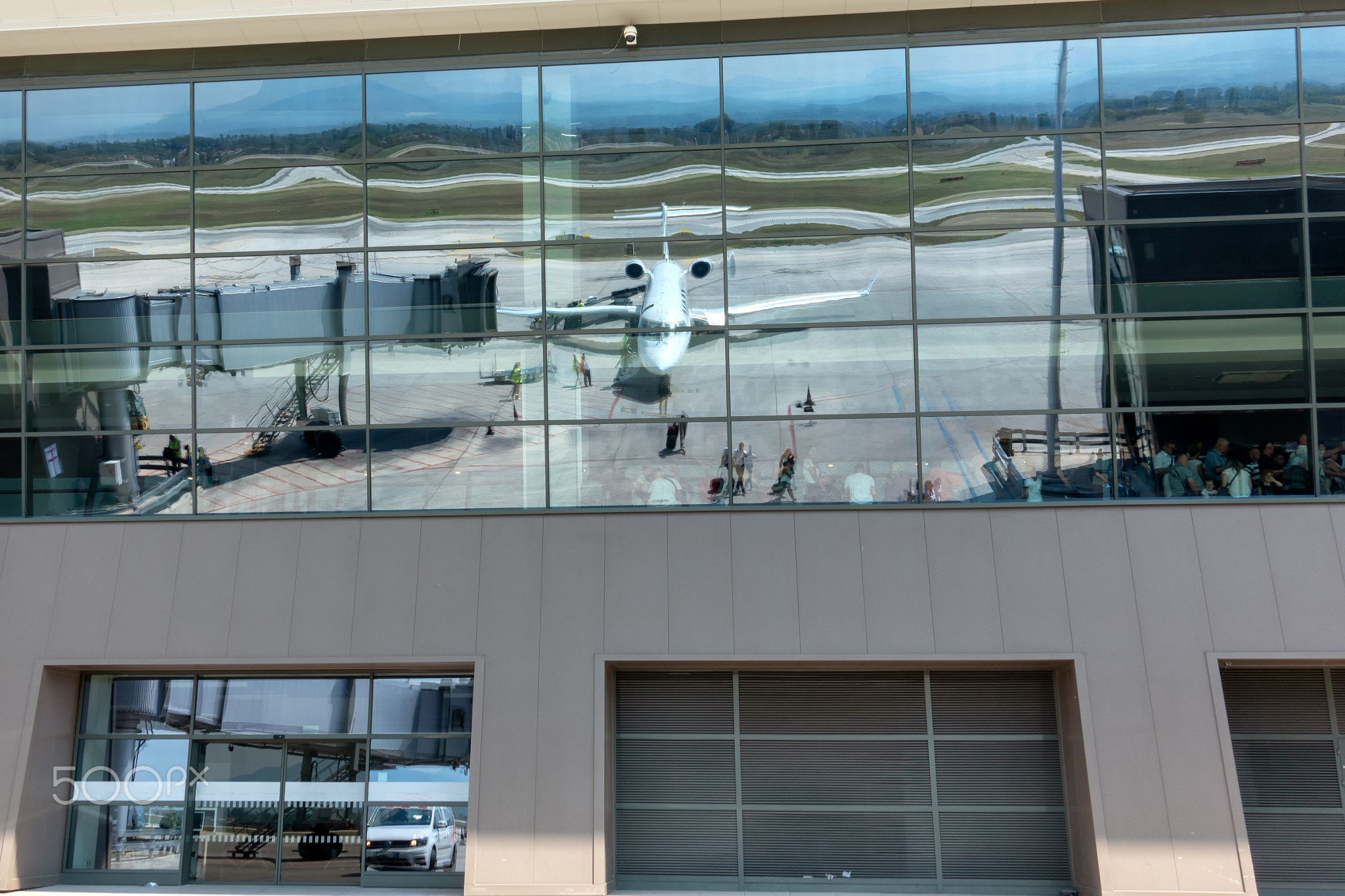 Reflection of passenger jet airplane in glass windows of airport terminal building