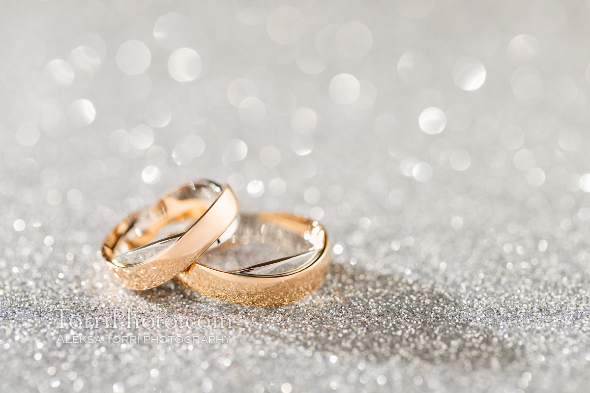Silver sparkling glitter bokeh background with golden wedding ri