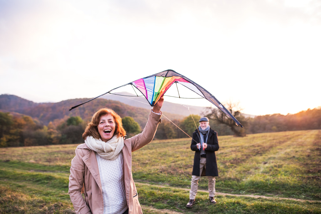 Carefree senior couple flying a kite in an autumn nature at sunset. by Jozef Polc on 500px.com
