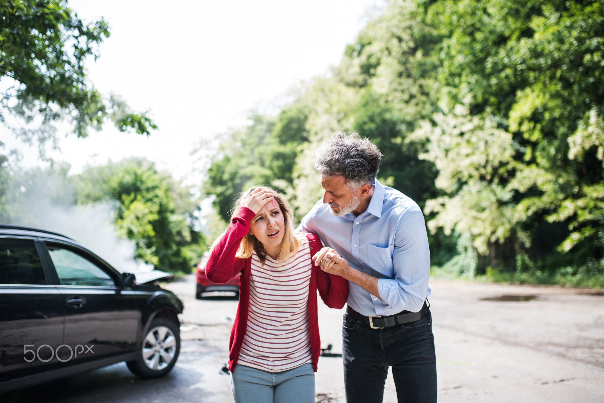 A mature man helping a young woman to walk after a car accident.