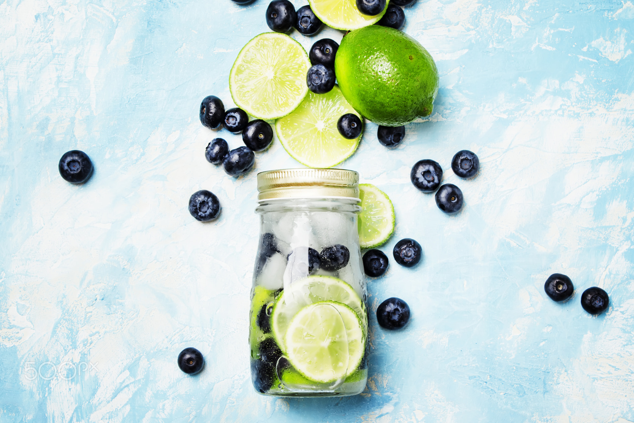 Summer refreshing beverage with blueberry, lime and ice in glass