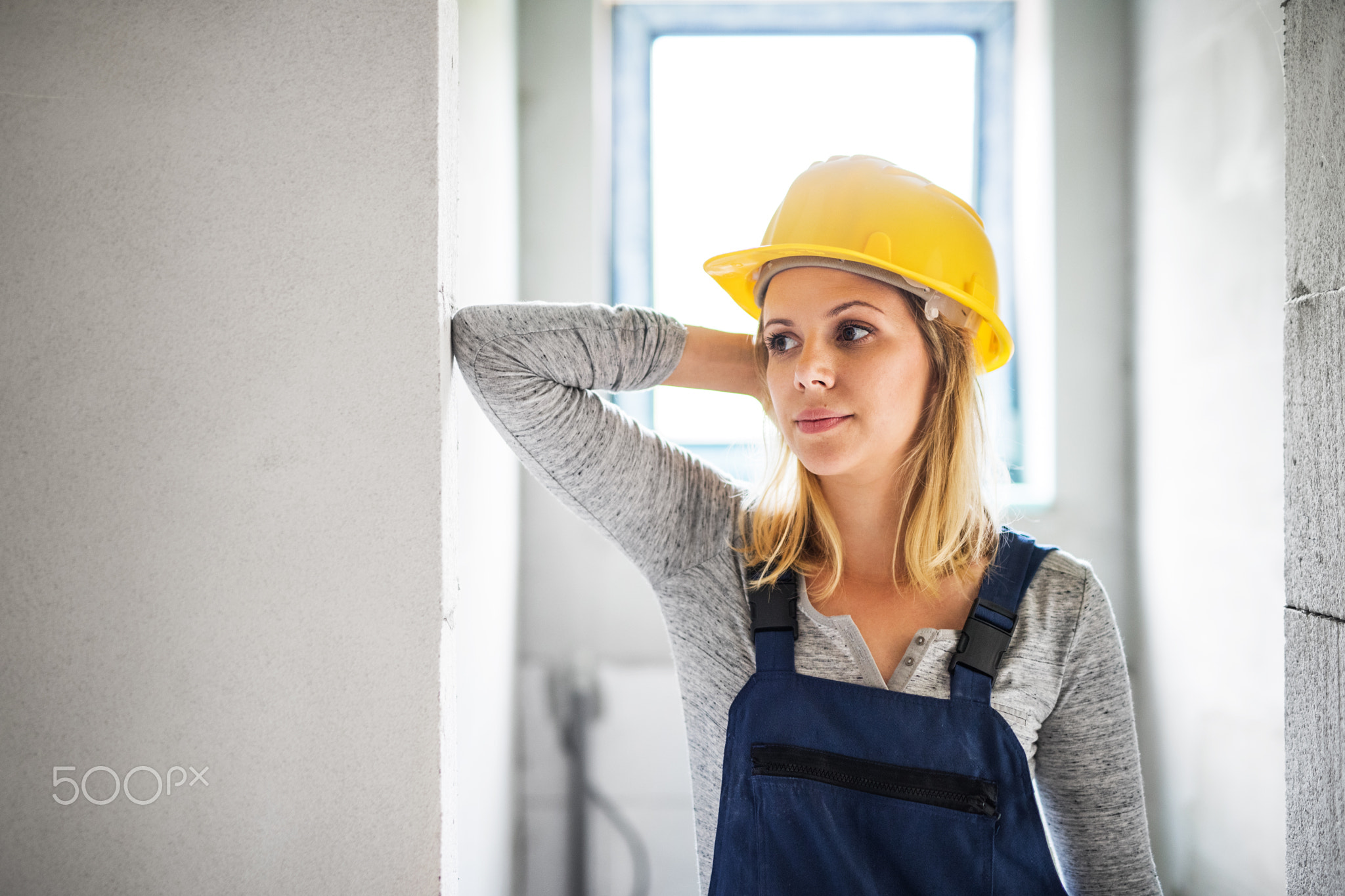 Young woman worker with a yellow helmet on the construction site.