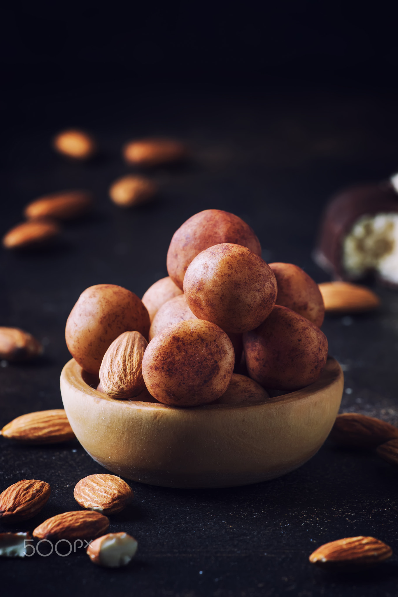 Marzipan, round almond candies in wooden bowl on dark table, sel