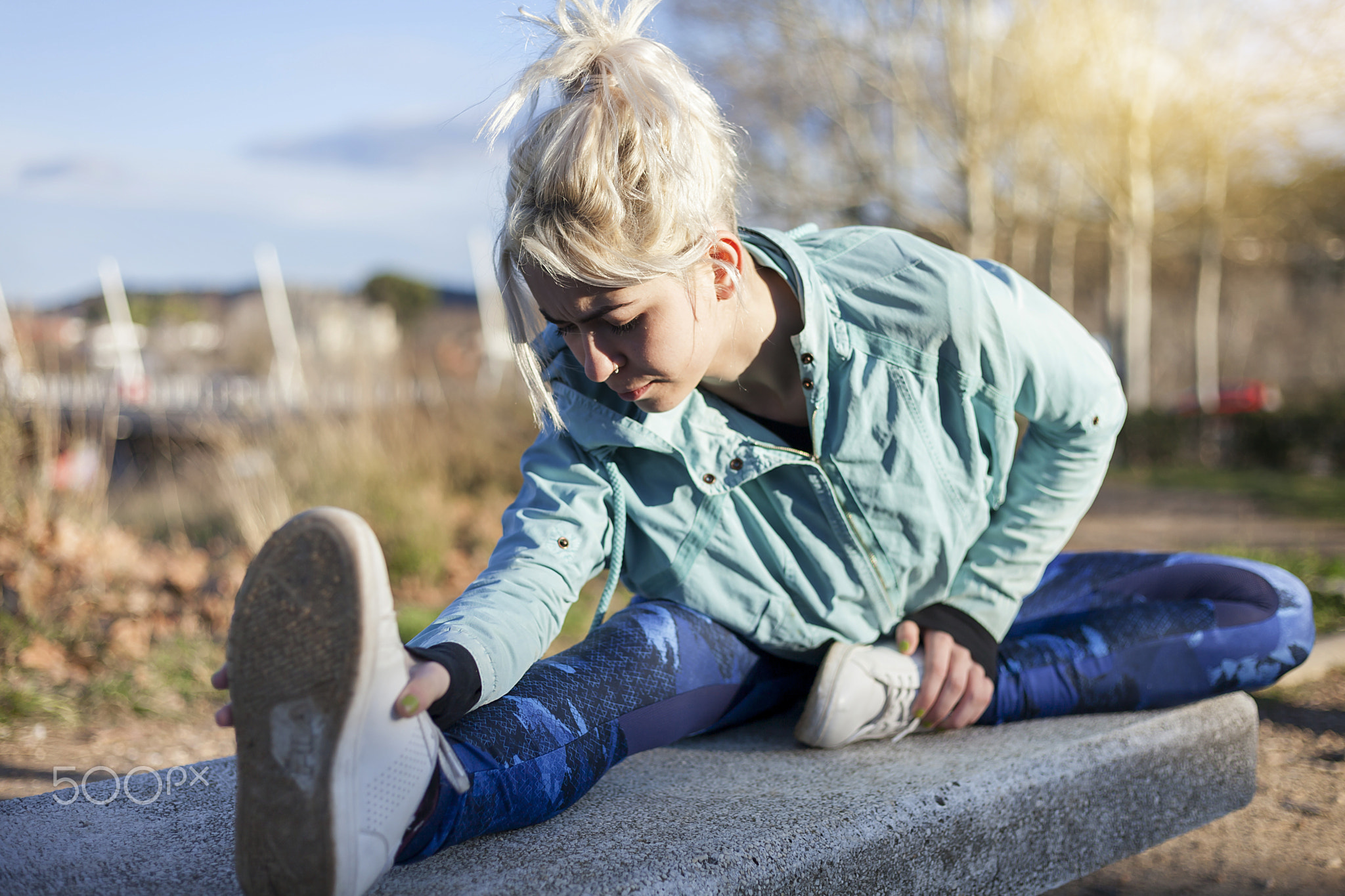 A beautiful young blonde woman stretching outdoors