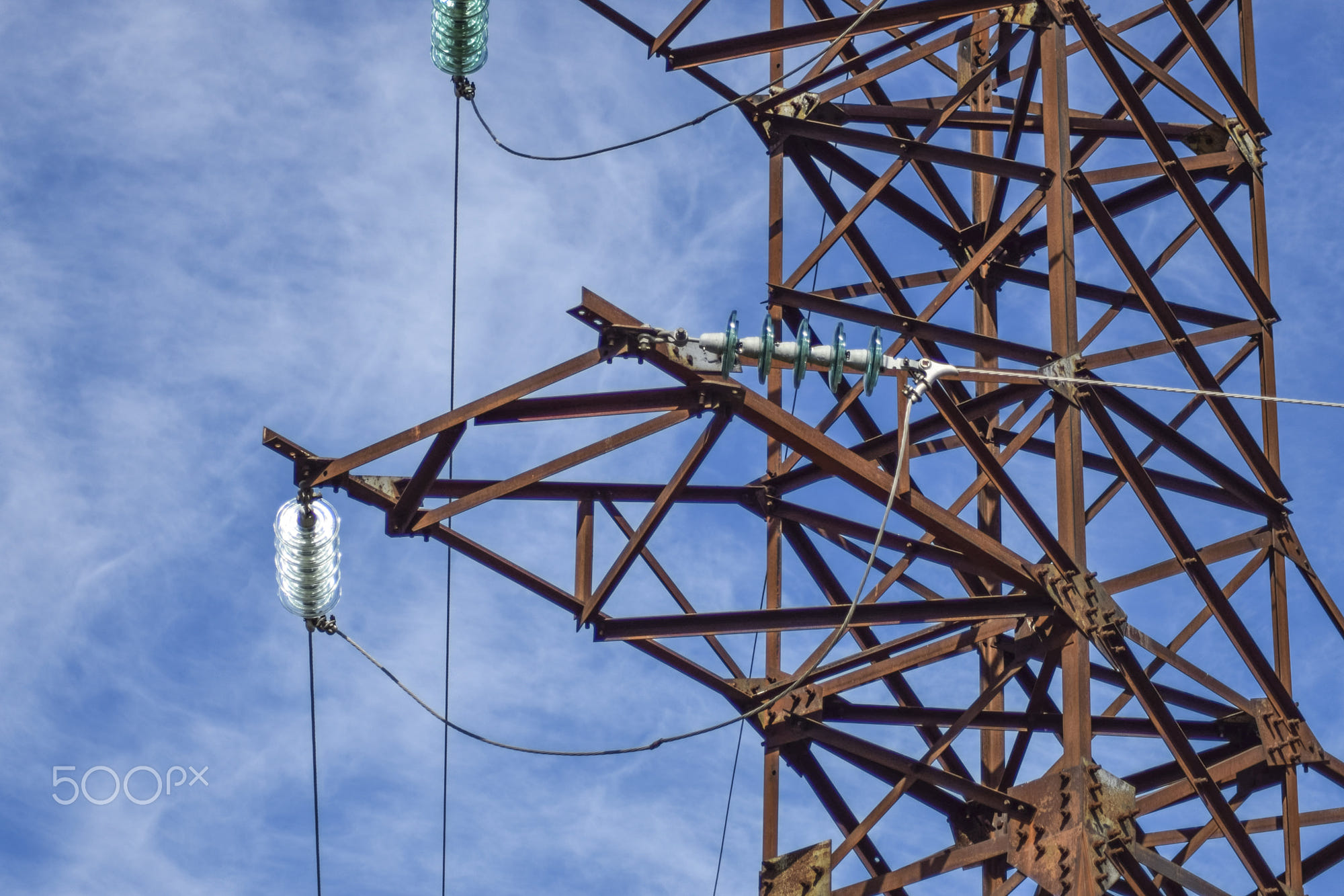 Supports high-voltage power lines against the blue sky with clou: Supports high-voltage power lines against the blue sky with clouds. Electrical industry.