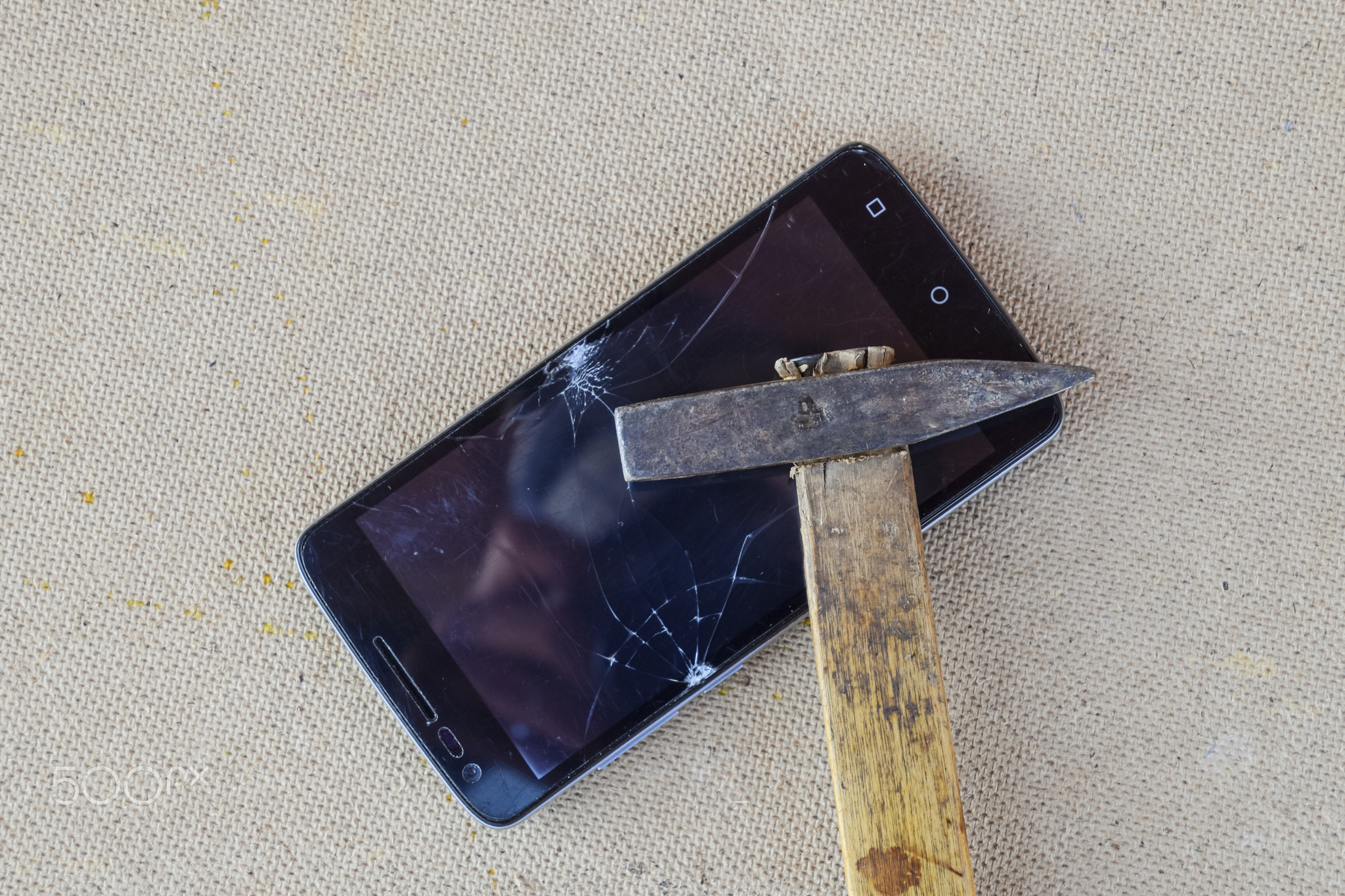 Hammer and smartphone. The screen of the smartphone, a broken ha