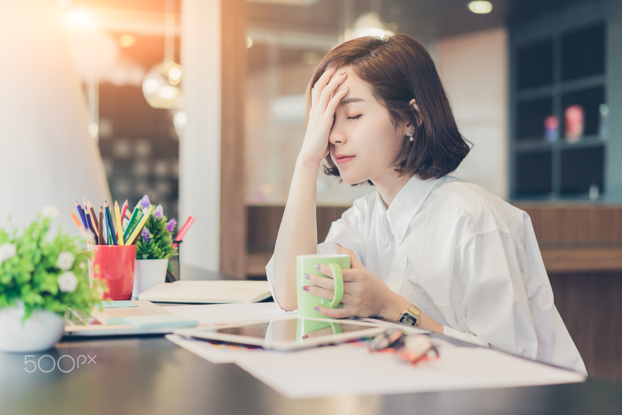 Young beautiful asian woman working on desk with tablet and headache in coworking spaces.