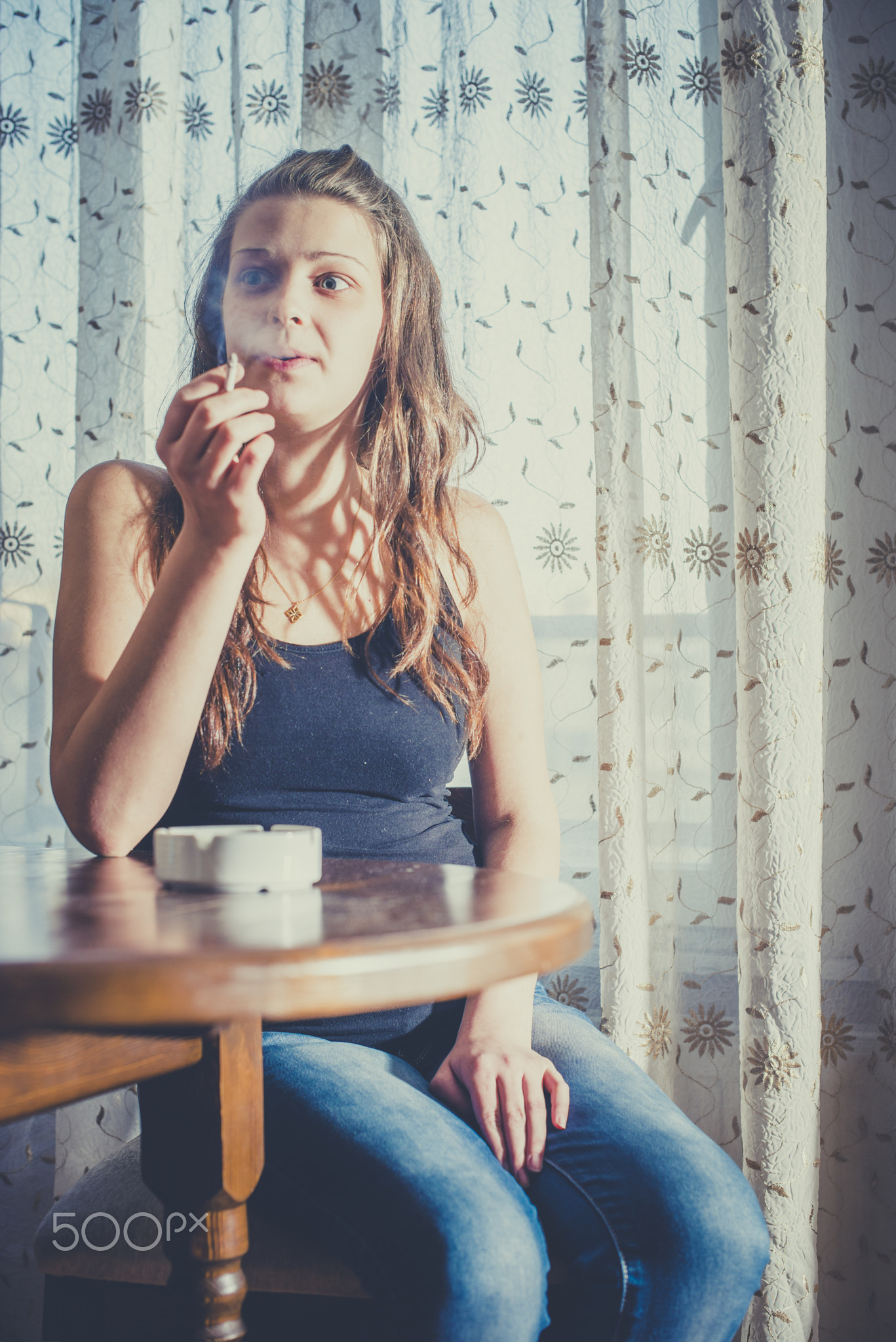 Girl smokes cigarette and holds ashtray.