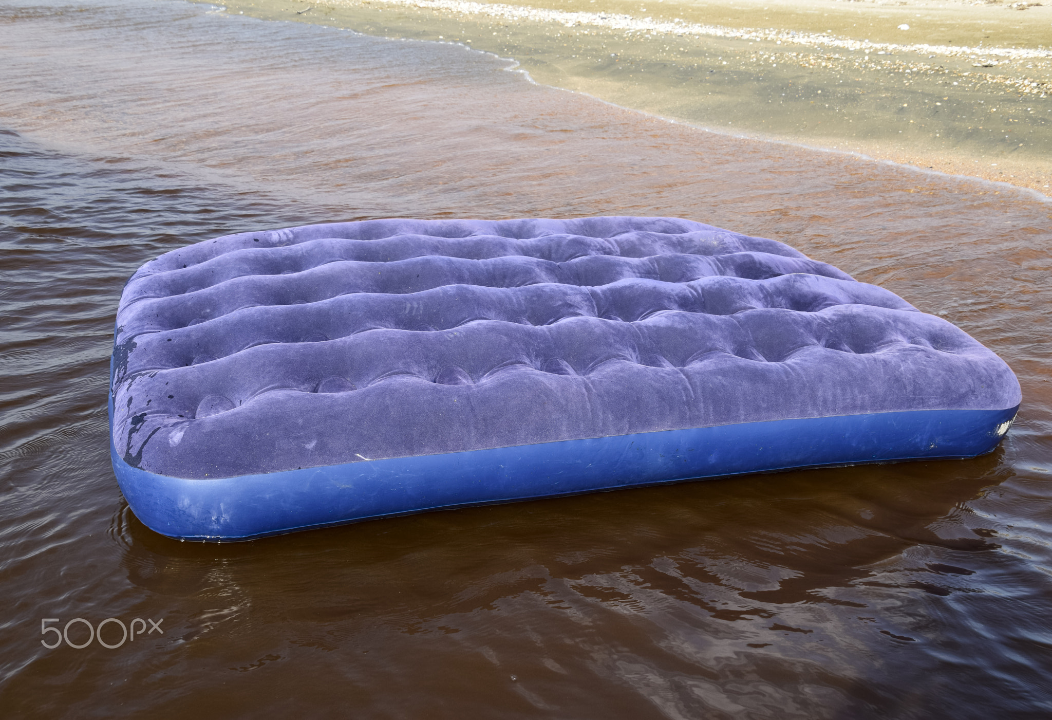 Blue inflatable mattress swimming in the pond