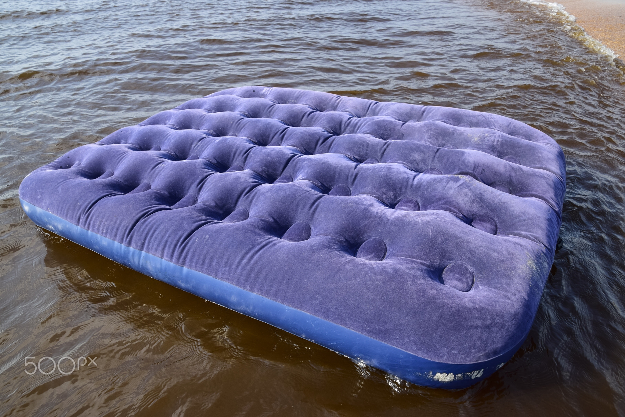 Blue inflatable mattress swimming in the pond