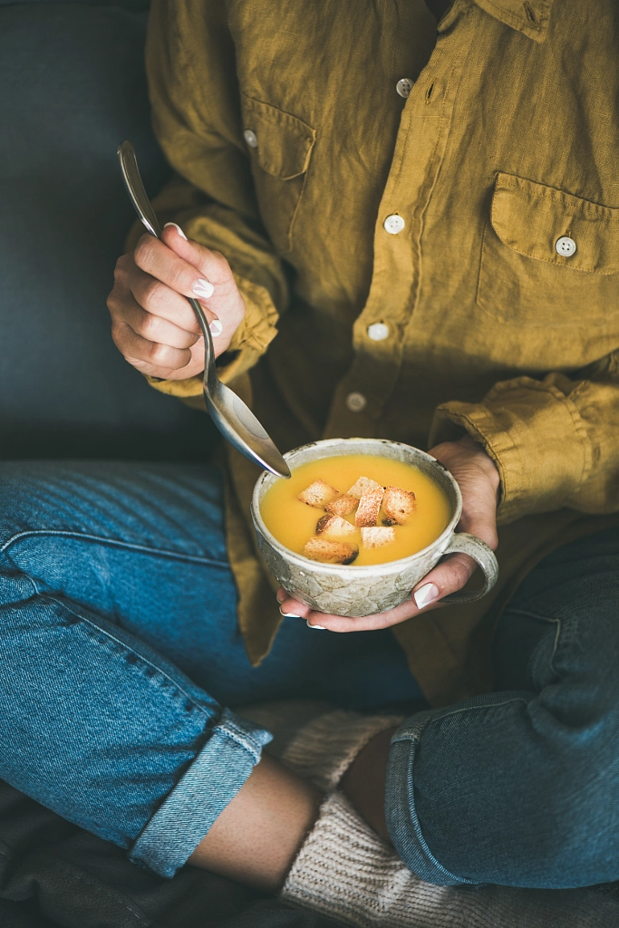 Woman sitting and eating warming pumpkin soup from mug by Anna Ivanova on 500px.com