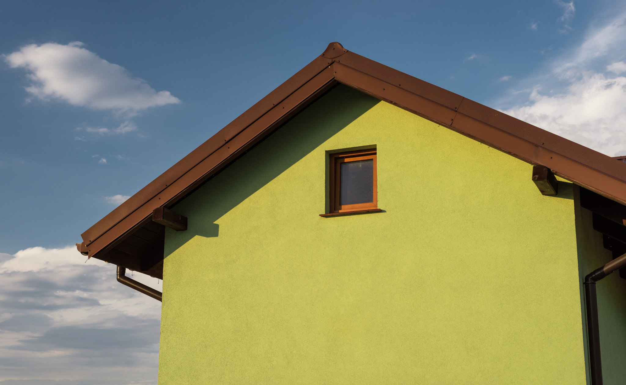 Bright green house facade with visible roof soffit