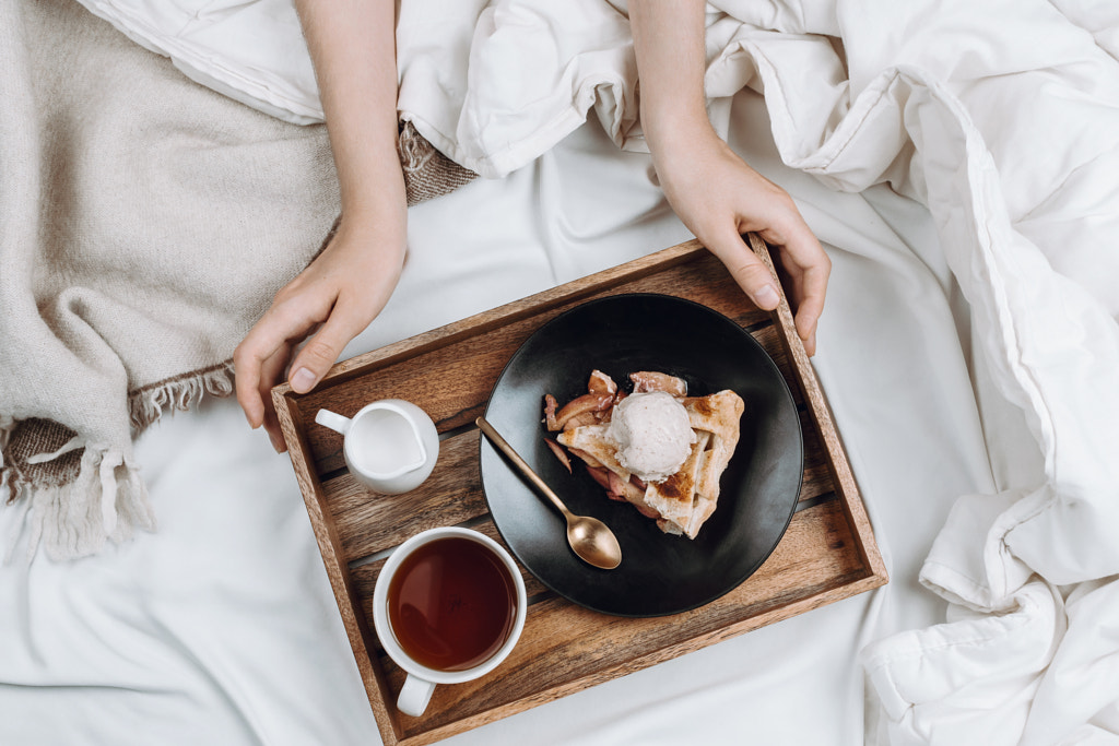 Cozy flatlay of bed, woman's hands holding wooden tray with vega by Nataly Lavrenkova on 500px.com