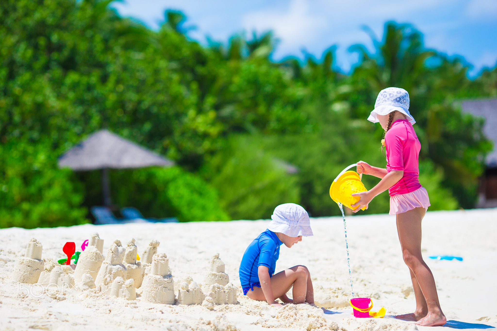 Adorable little girls playing with beach toys during tropical vacation