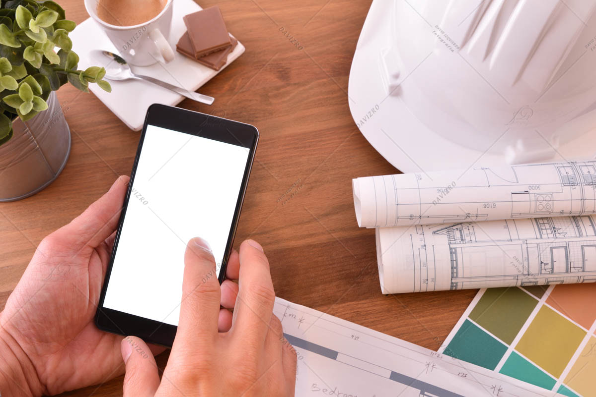 Hands using smartphone in an architect's office