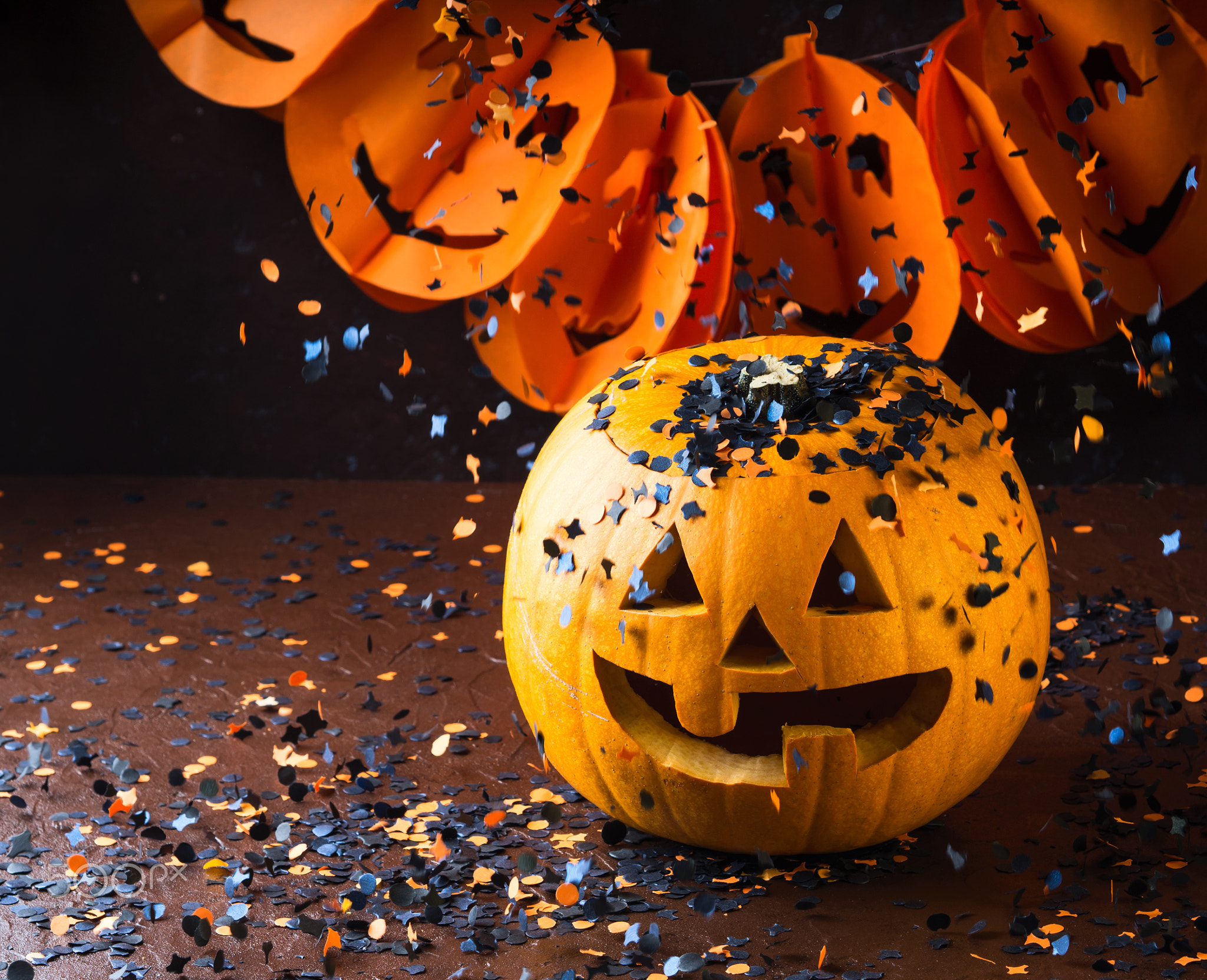 Halloween carved squash and confetti. Dark
