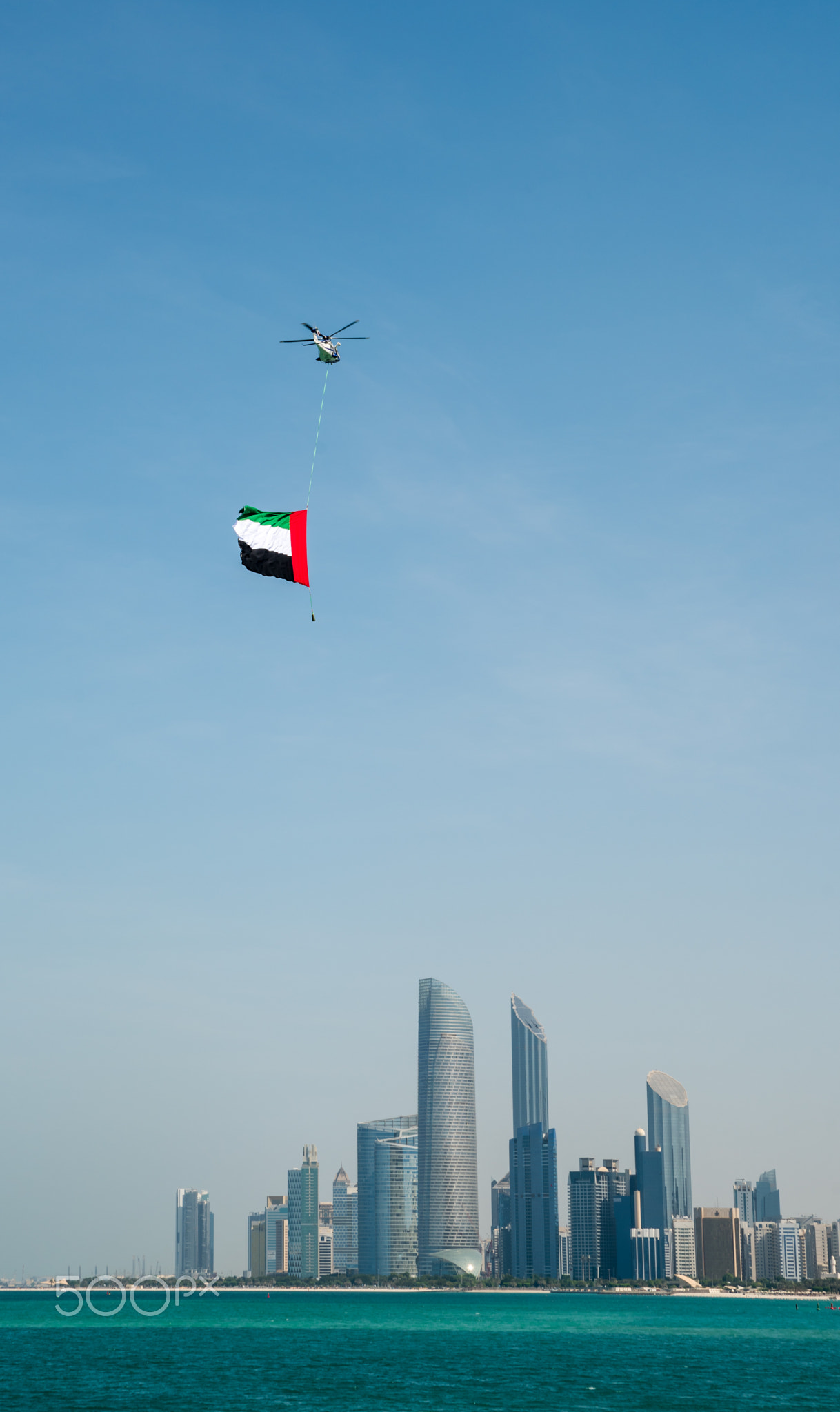 Helicpter hovering over city with UAE Flag on Flag Day