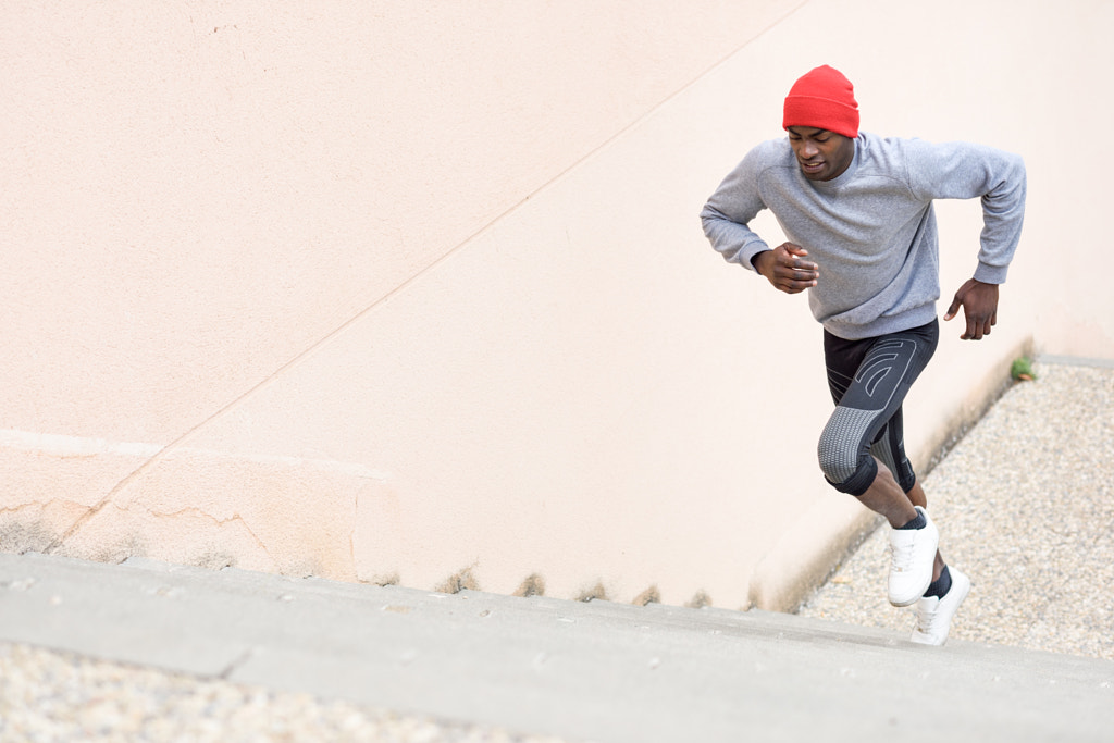 Black man running upstairs outdoors in urban background by Javier Sánchez on 500px.com