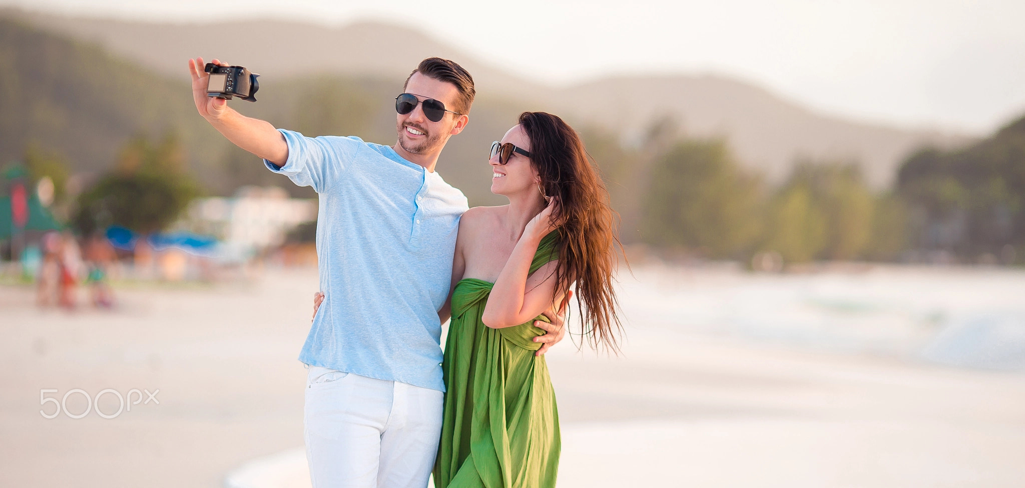 Happy couple taking a selfie photo on white beach.