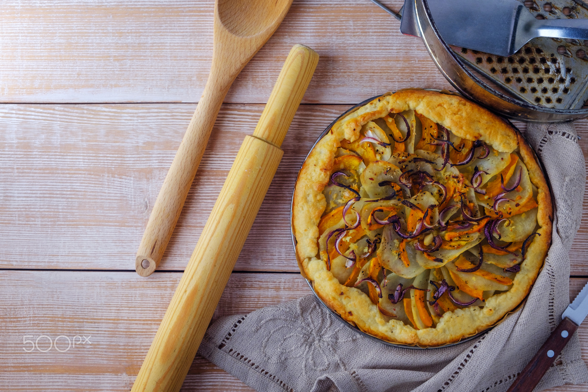 Homemade potato pie with pumpkin and onion on wooden background.