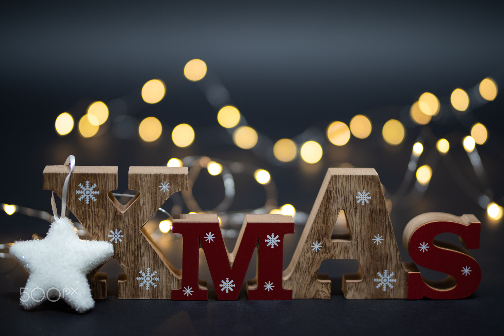 Wooden Xmas text decoration with high golden blurred bokeh behind