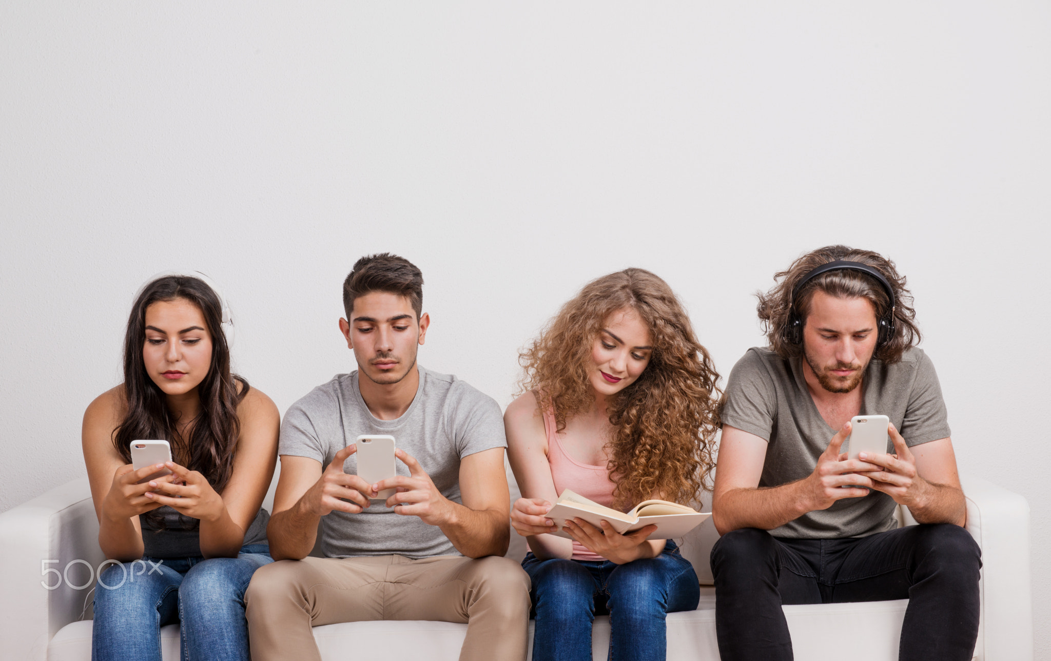Young group of friends using modern technology and traditional source of information.