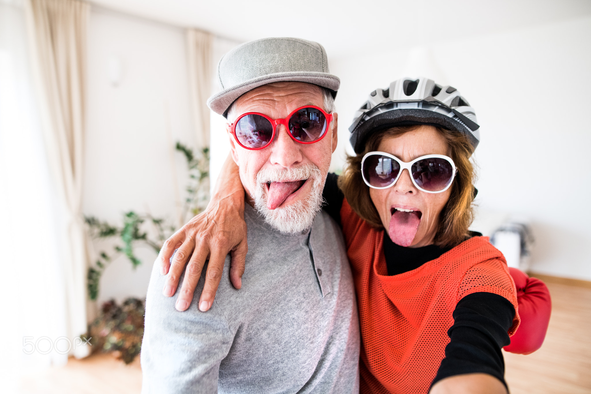 A senior couple with sunglasses having fun at home.