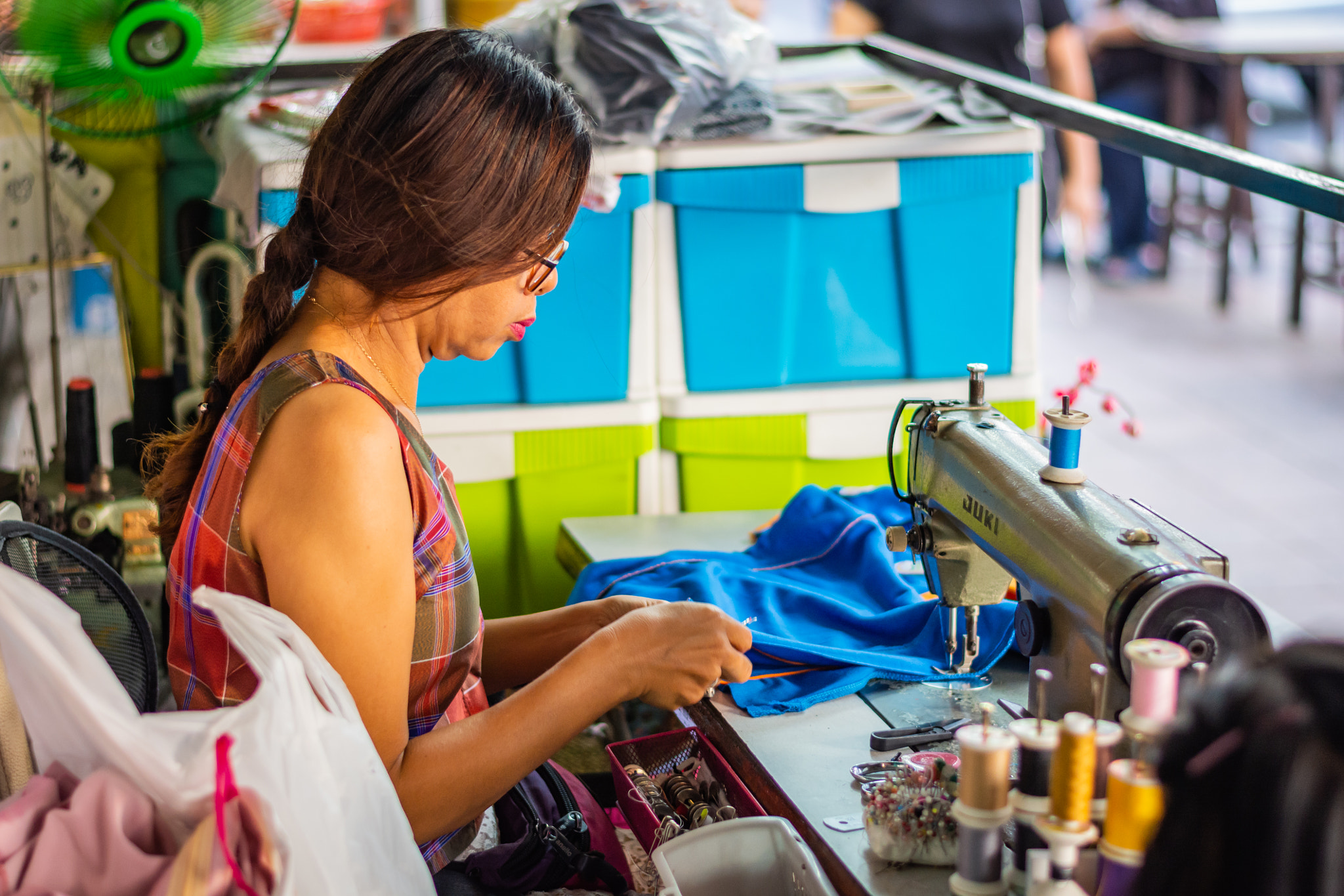 Woman sewing in a tailor shop on a street