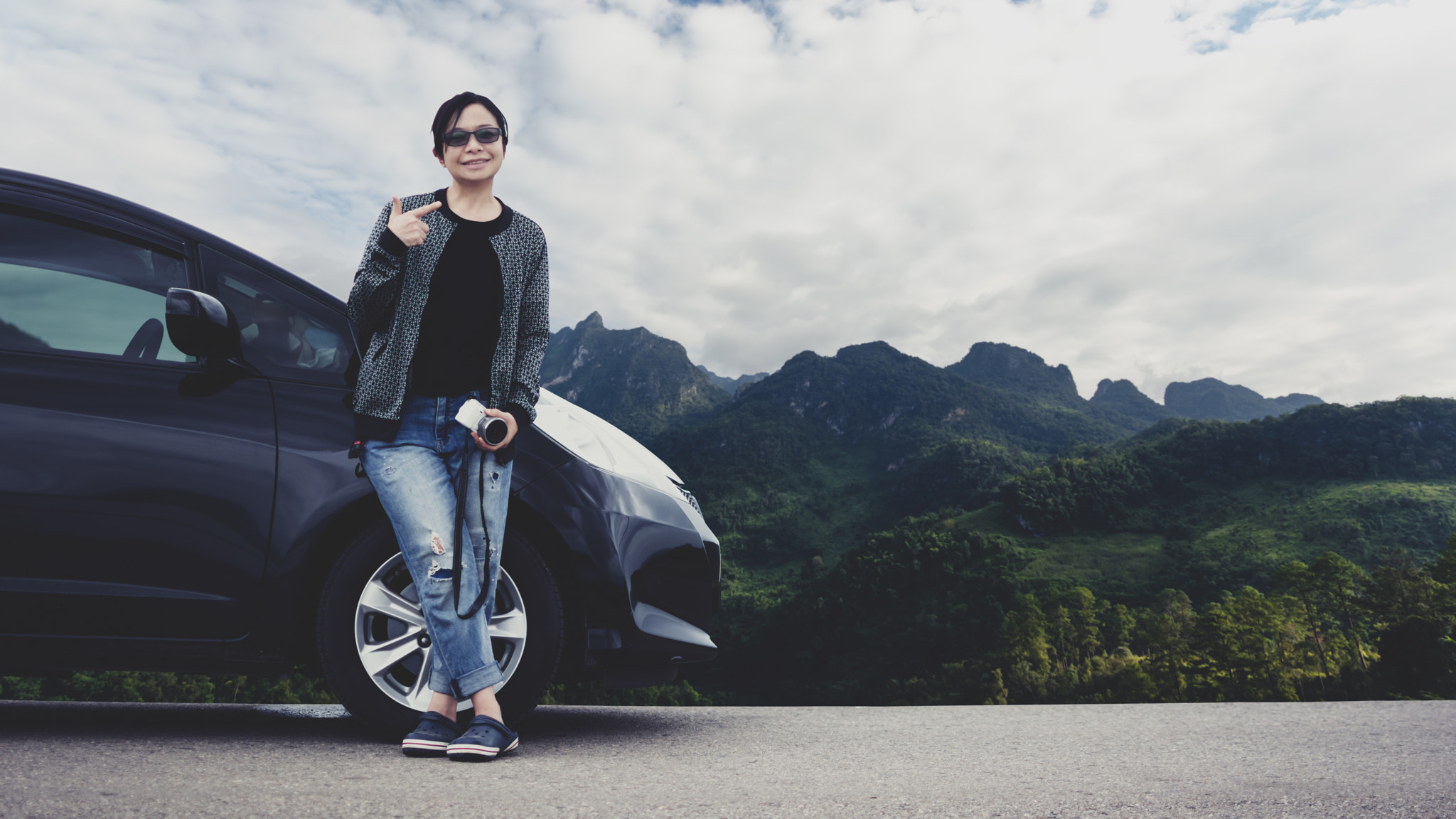 A Woman with A car on the road and Mountain in background. Lifes
