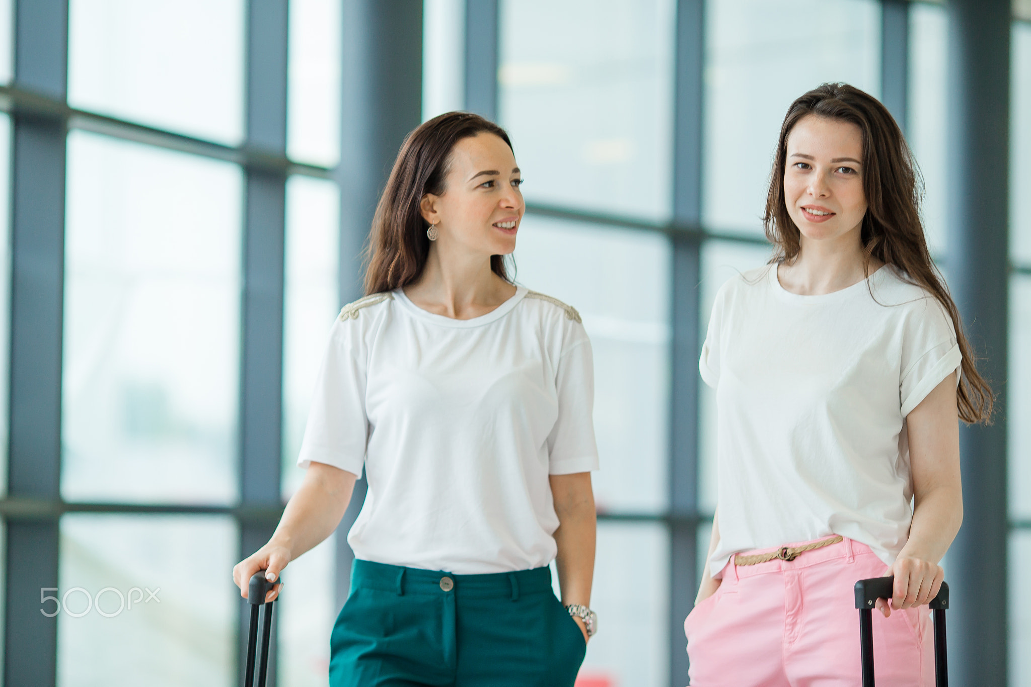 Young women with baggages in international airport. Airline passengers in an airport lounge...