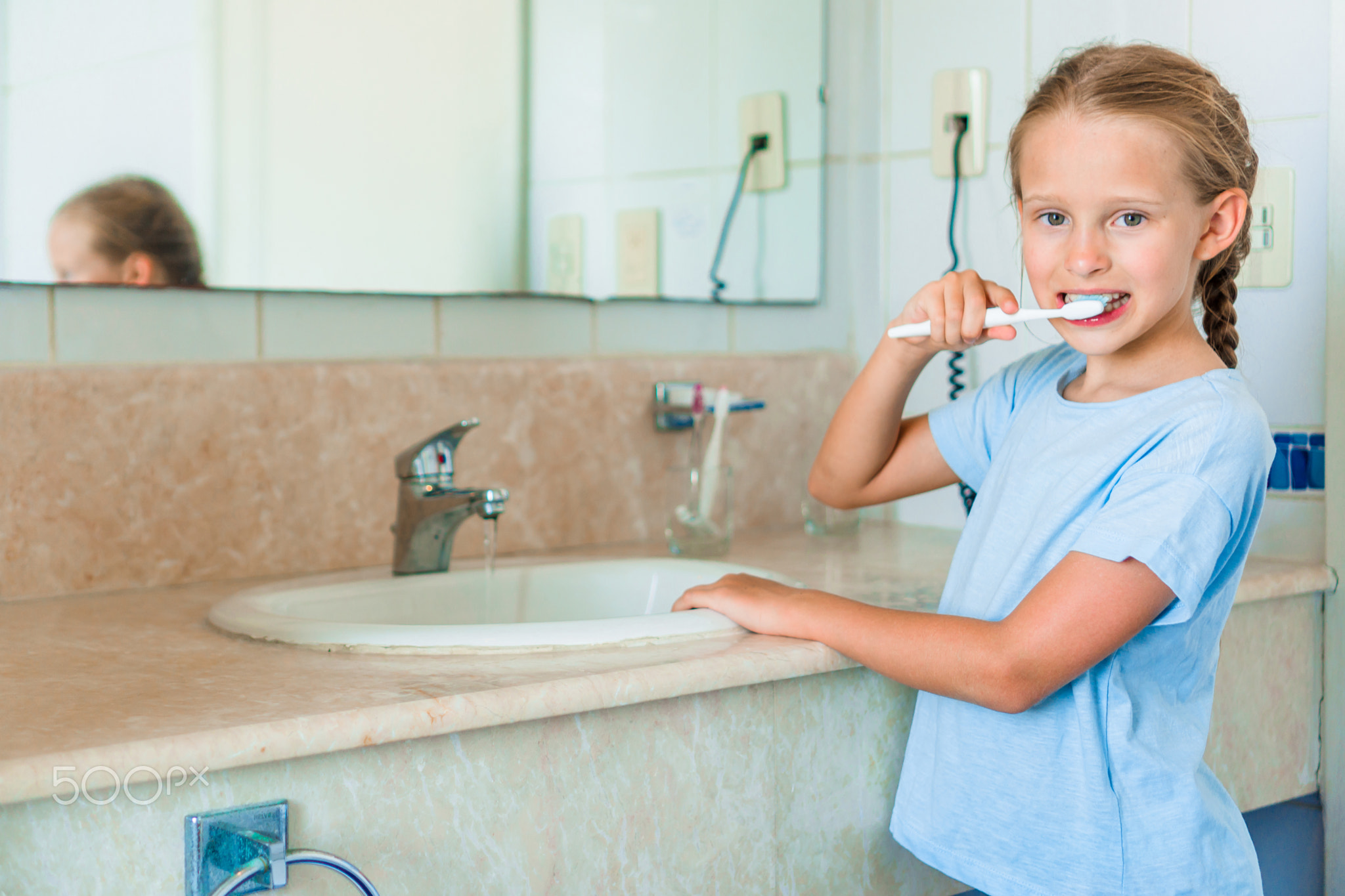Little smile girl brushes teeth in the bathroom