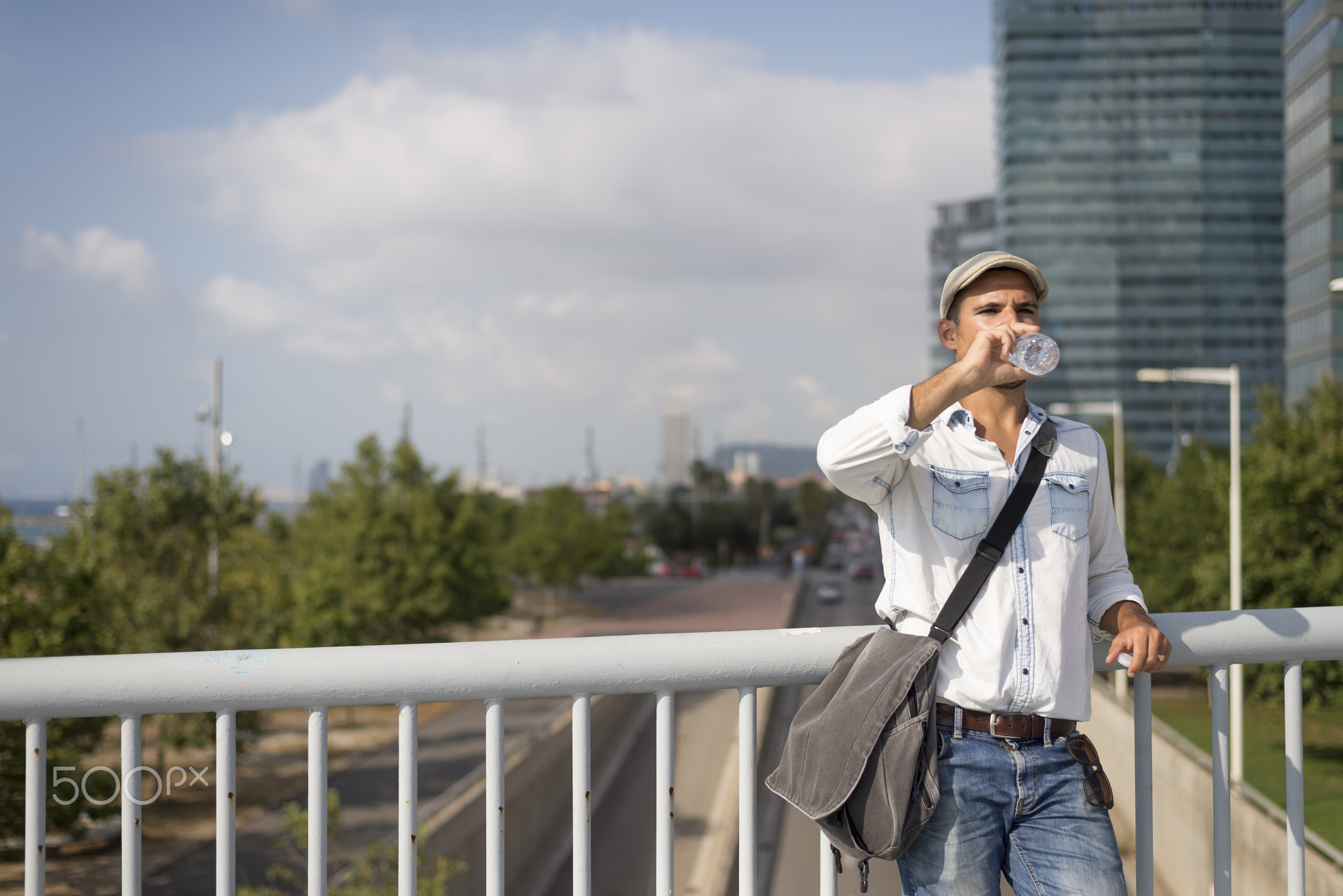 portrait of a young and masculine man drinking a water outside