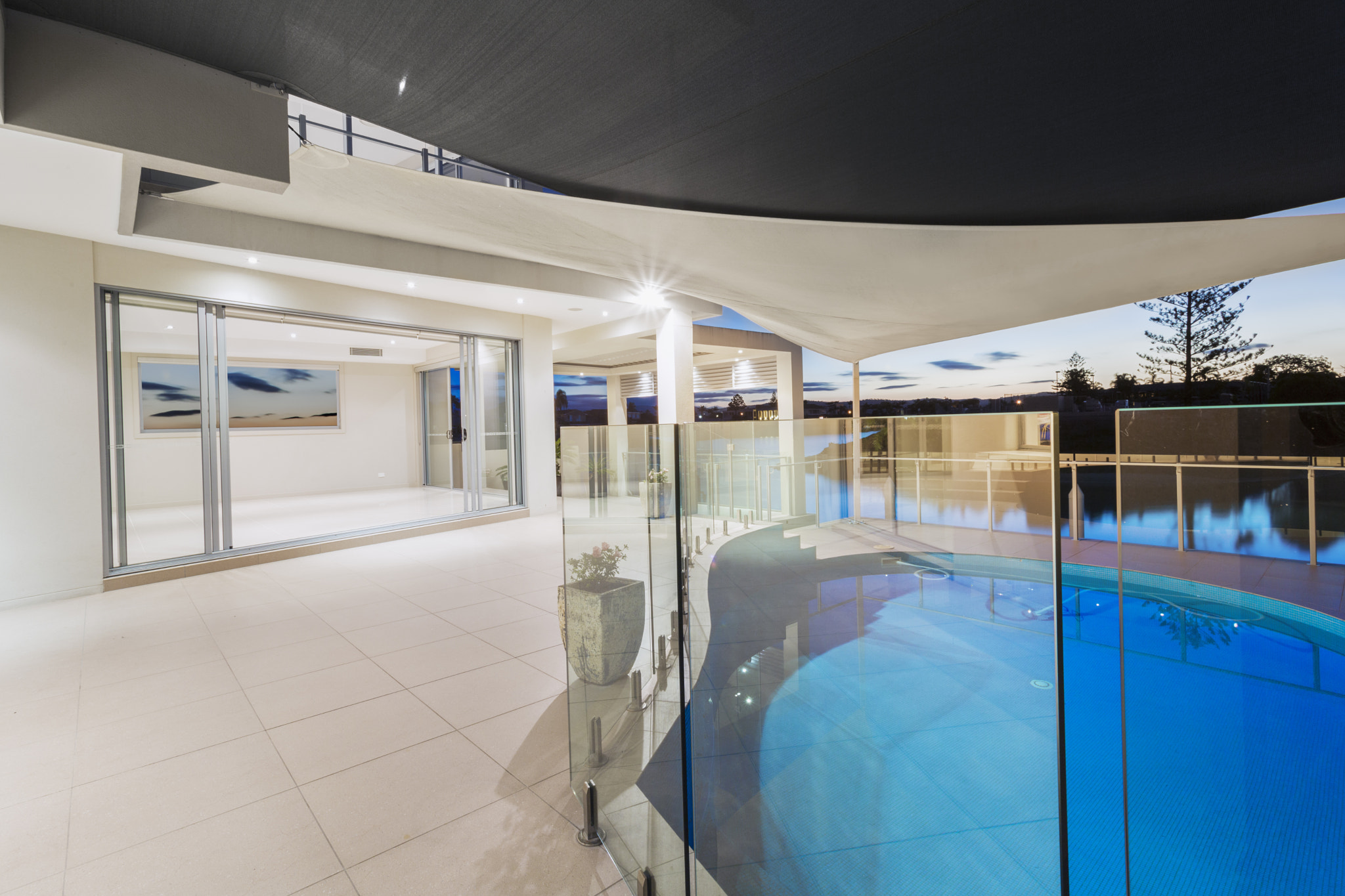 Pool and deck in modern mansion at dusk.