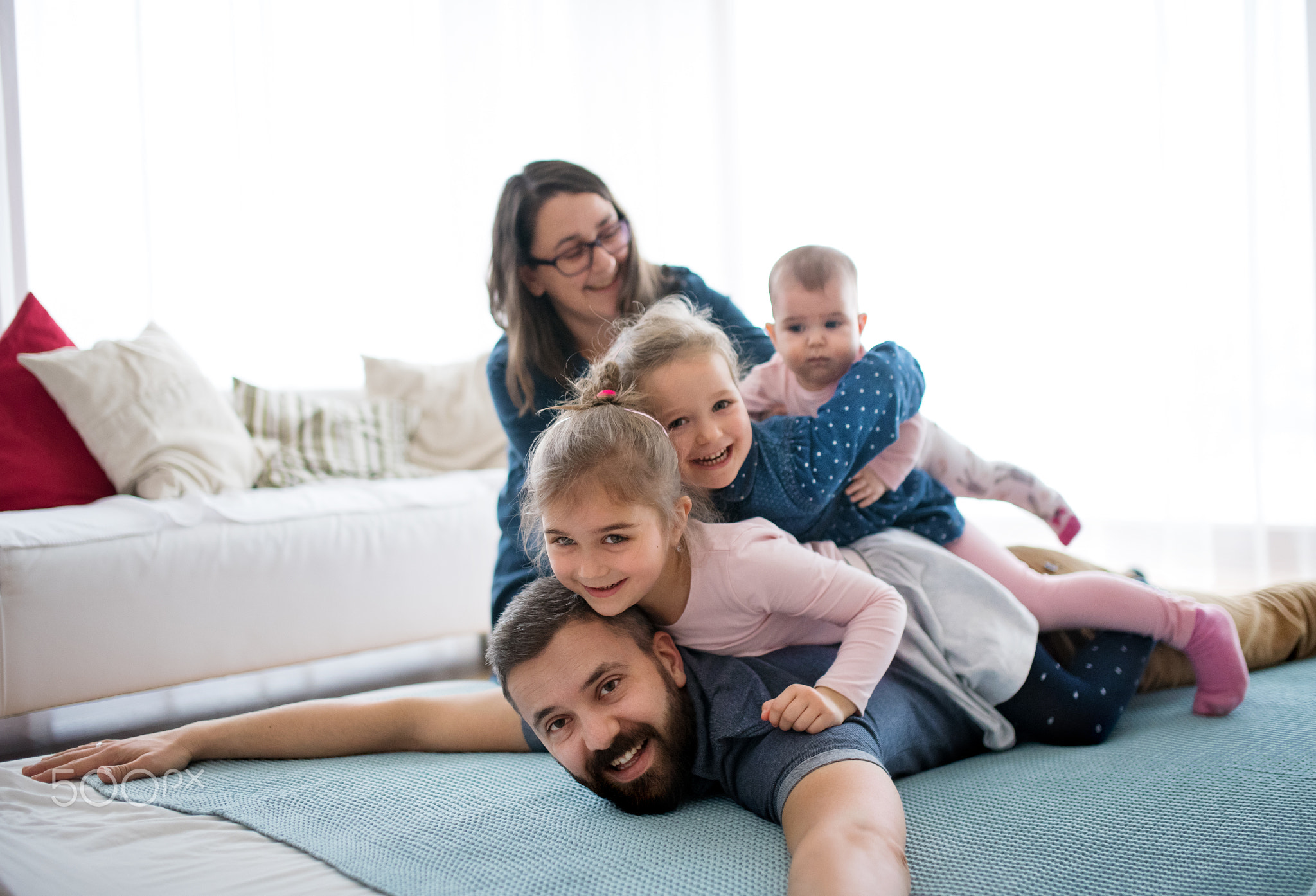 A portrait of young family with small children lying on floor indoors.