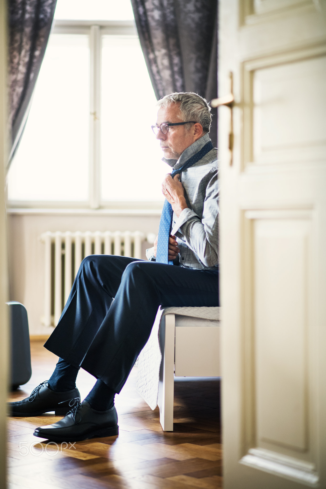 Mature businessman on a business trip in a hotel room, getting dressed.