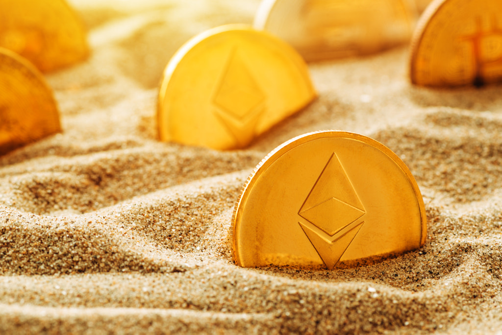 Golden Ethereum coin in sand by Igor Stevanovic on 500px.com