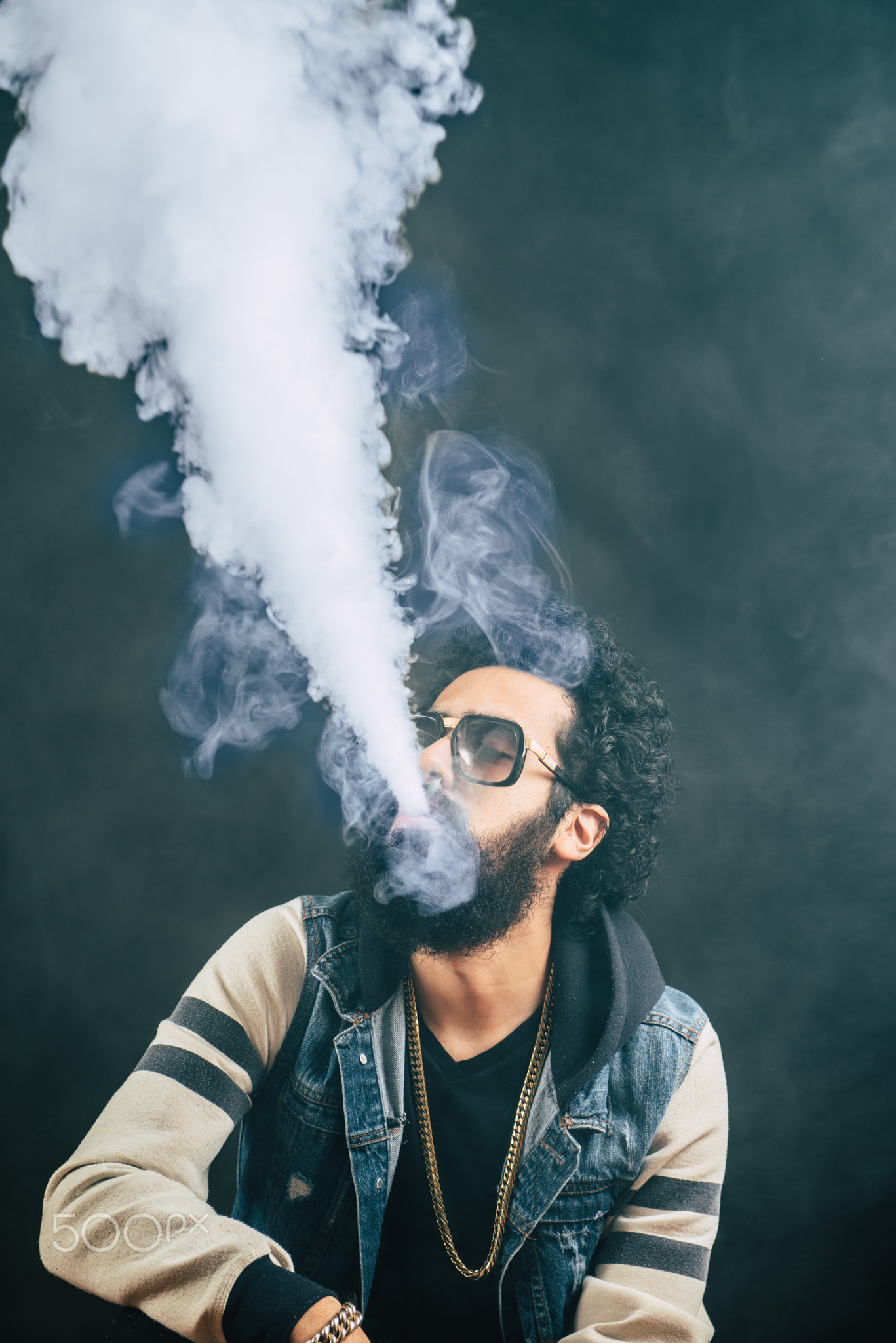 Young man with beard vaping an electronic cigarette upwards. Vaper hipster smoke vaporizer.