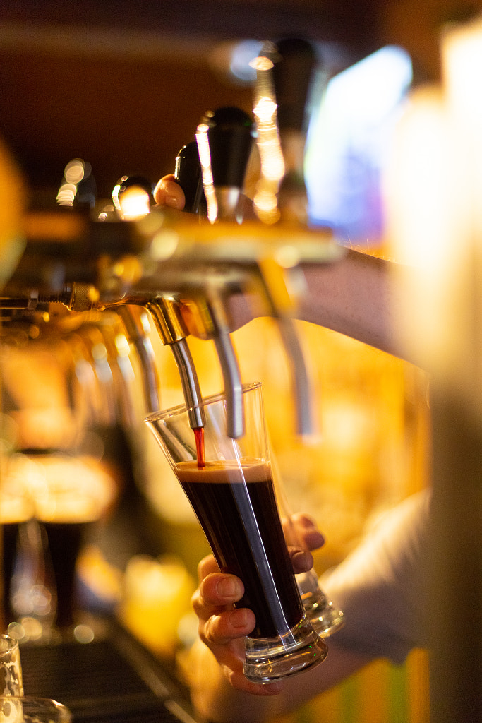 Dark beer is poured into a glass of beer tap by Oleghz Hz on 500px.com