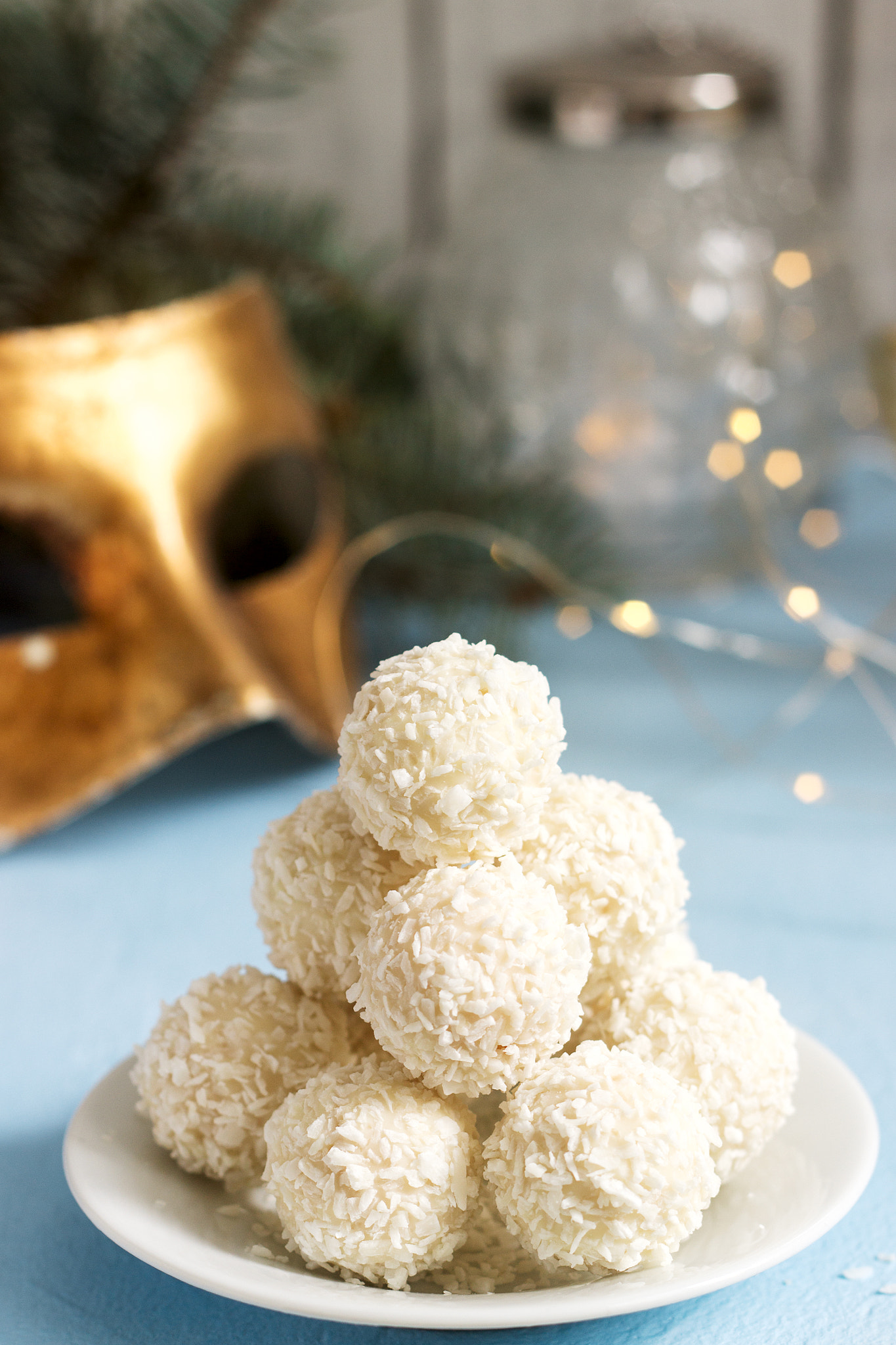 Coconut candies with white chocolate on a winter background with a garland, a candle and fir...