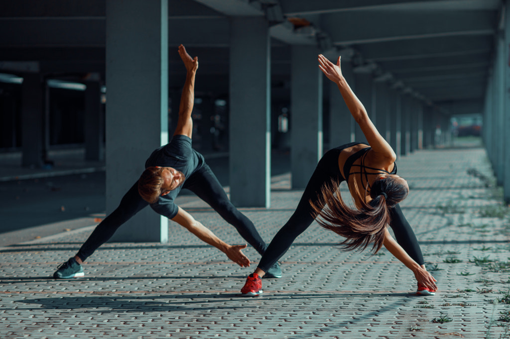 Young couple warming up in urban environment before jogging by Milenko ?ilas on 500px.com