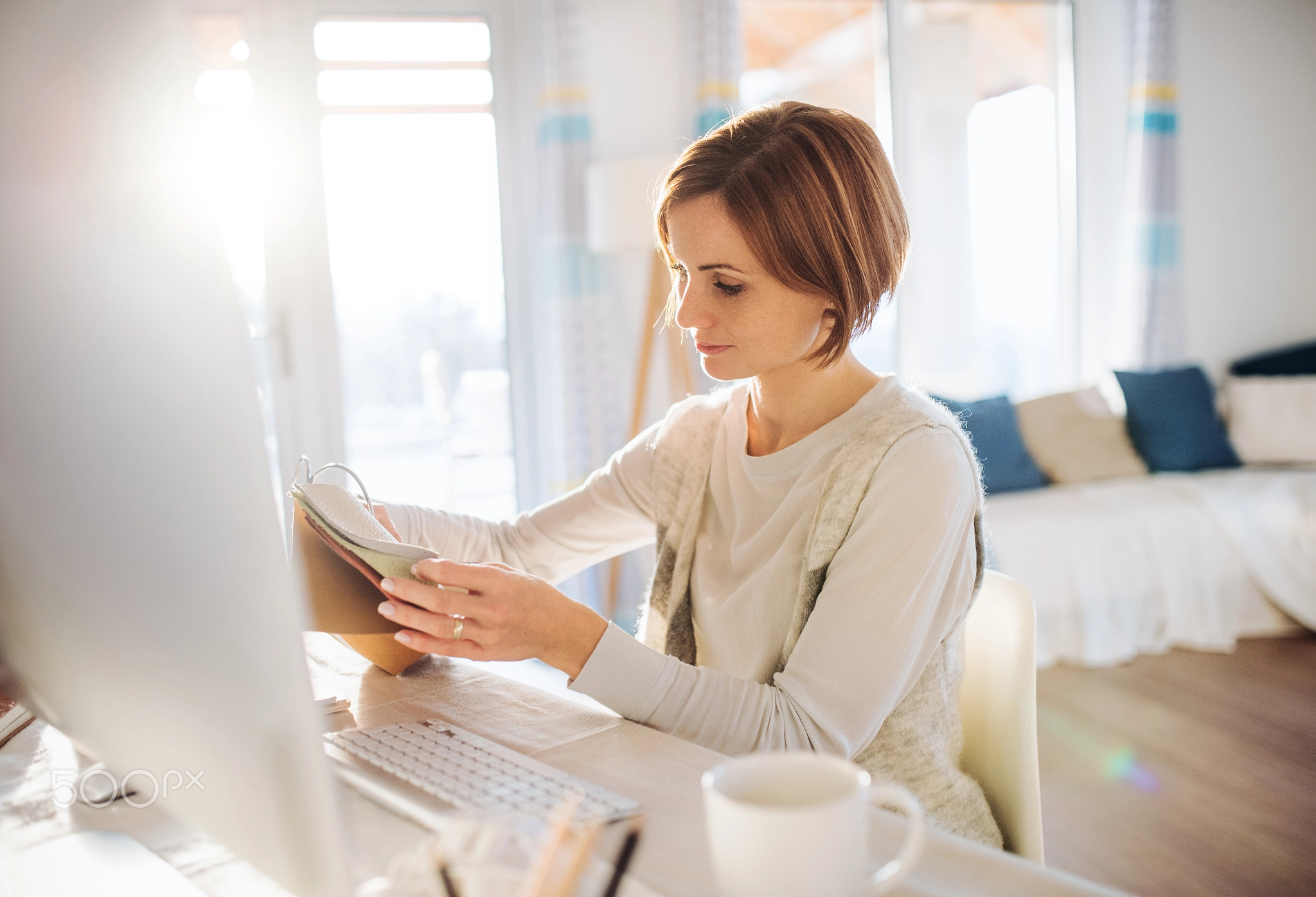 A happy young woman indoors, working in a home office.