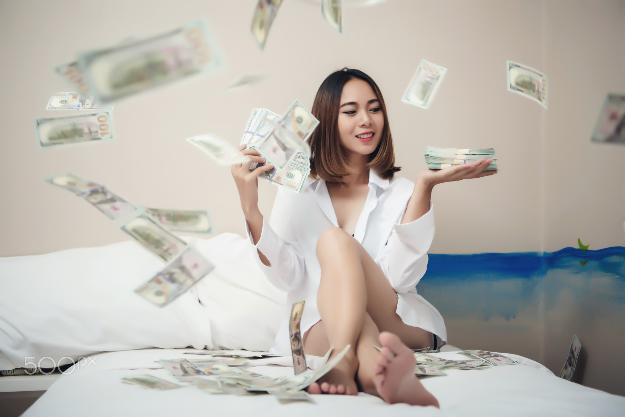 Beautiful woman laying in bundles of cash in the bed room