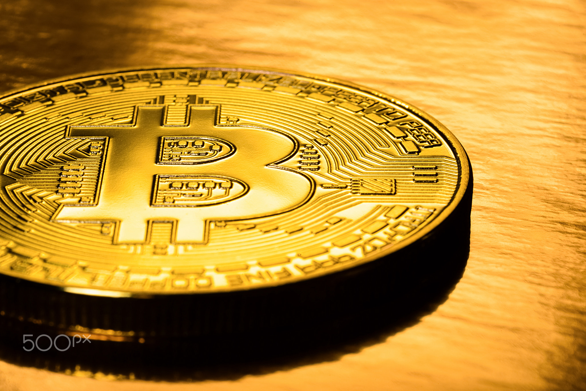 Golden bitcoin on a gold background. Physical e-cryptocurrency coins.