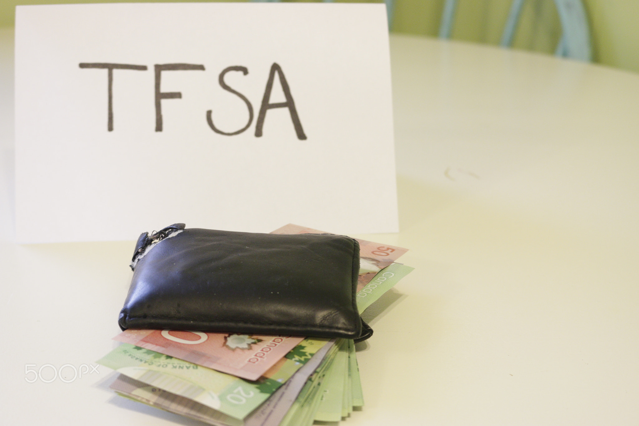 a sign that says TFSA next to a wallet that has money in it. Theme of Canadian savings. TFSA...