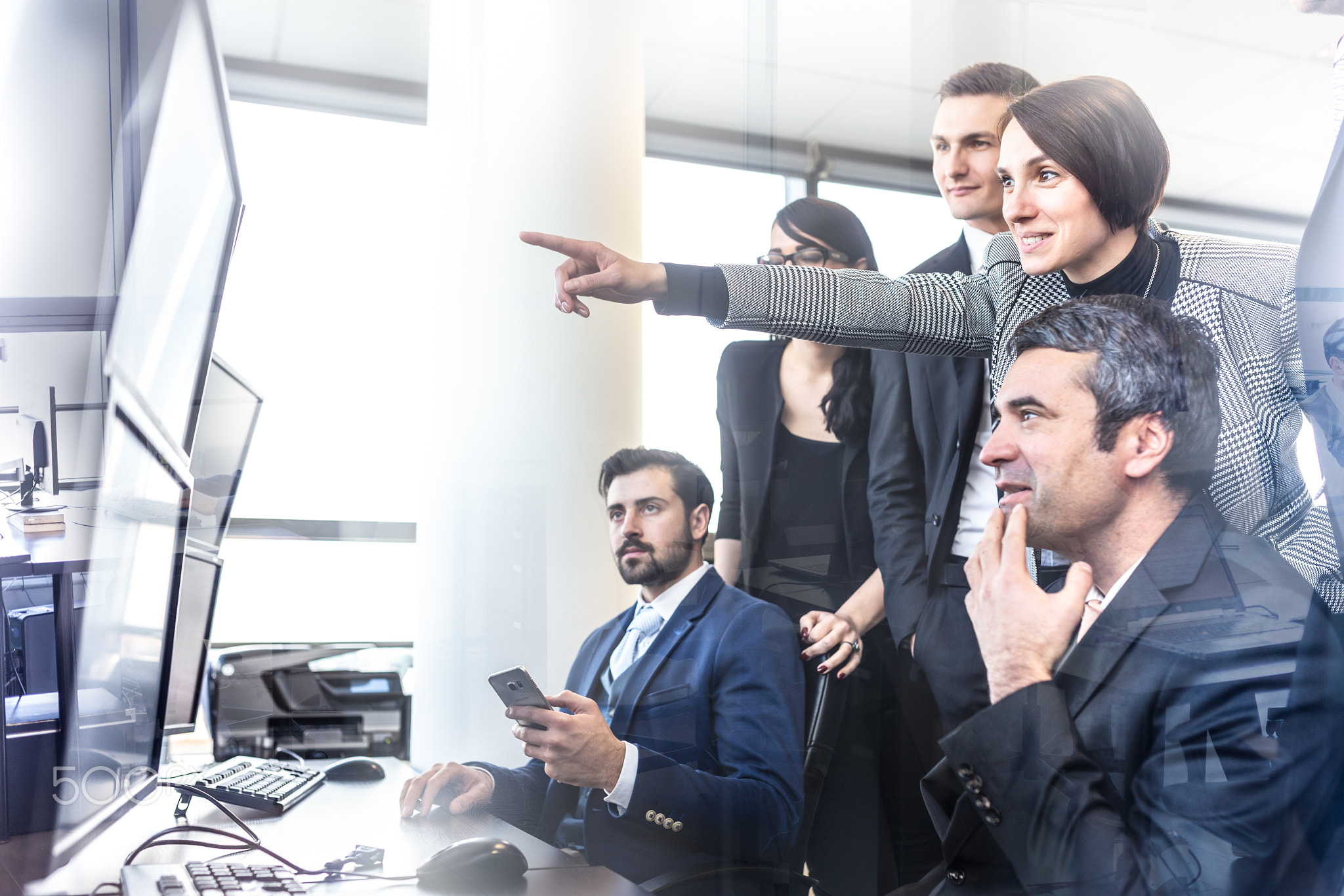 Successful business team looking at trade data on computer screens in corporate office.