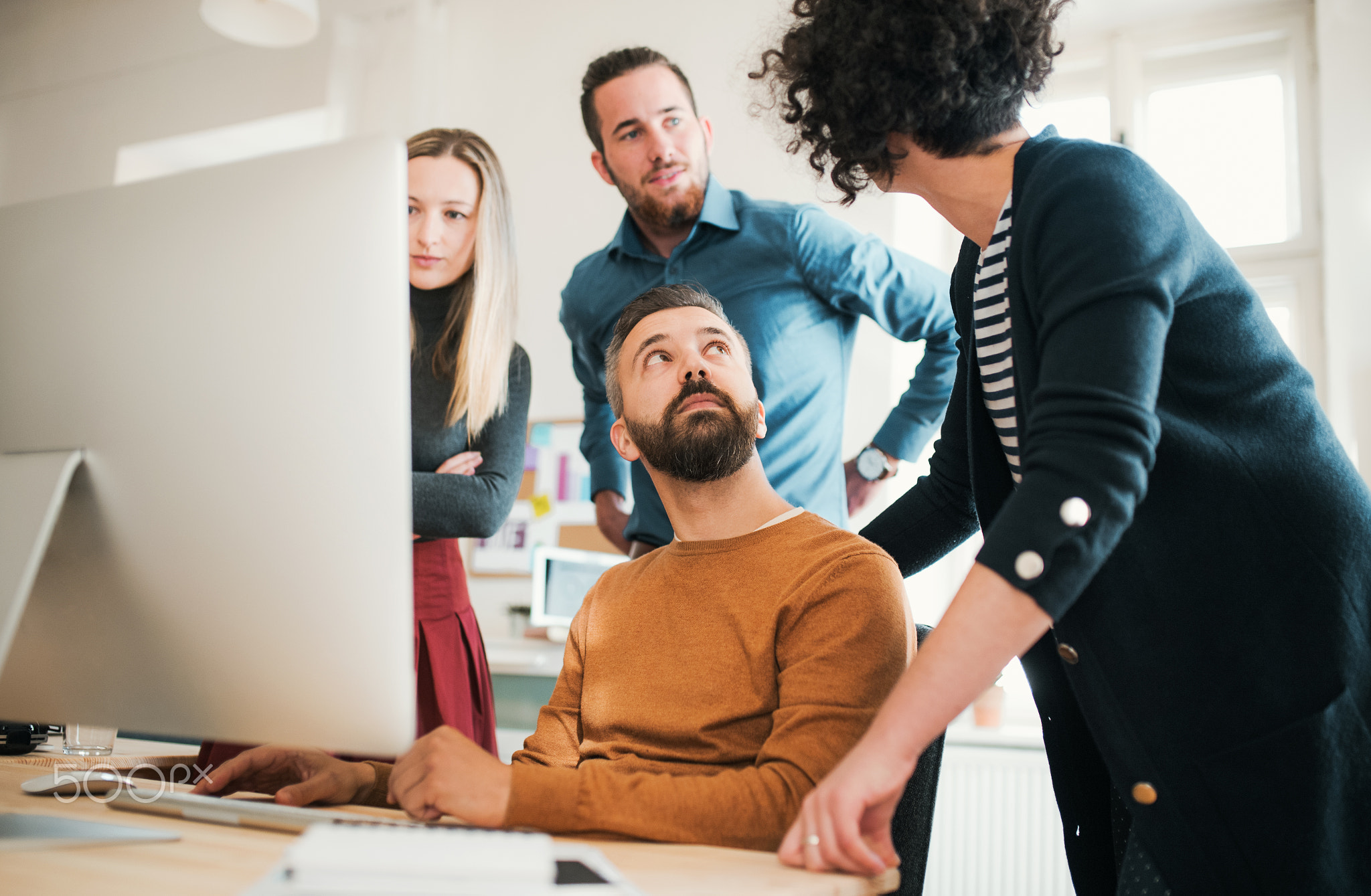 Group of young businesspeople with laptop having meeting in a modern office.