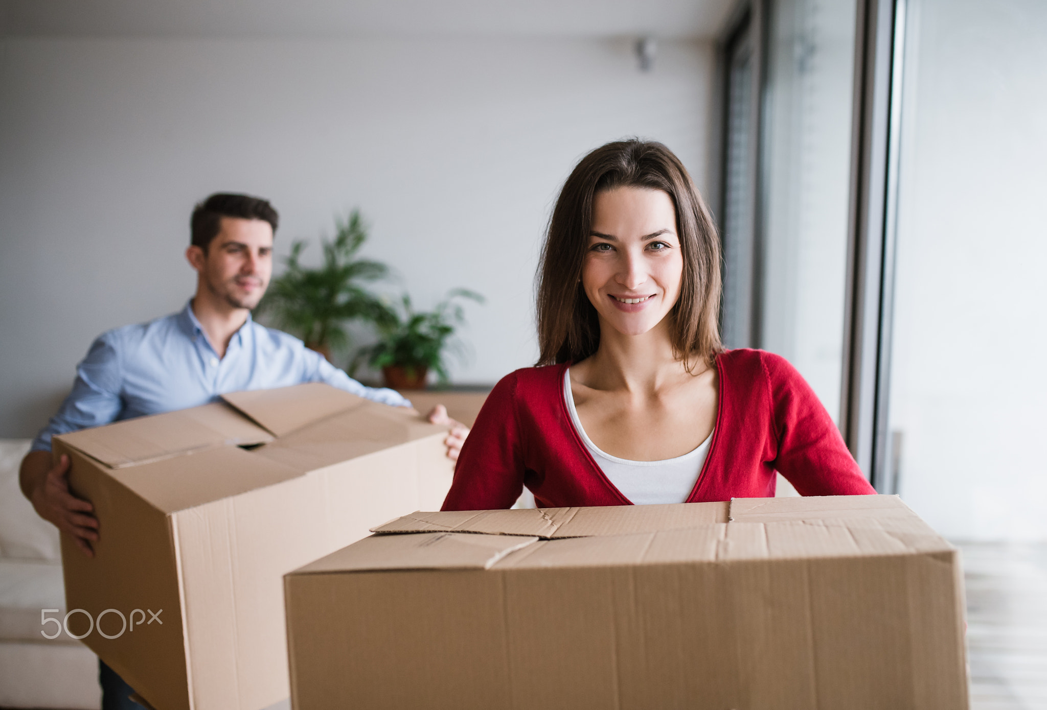 Young couple with cardboard boxes moving in a new home.