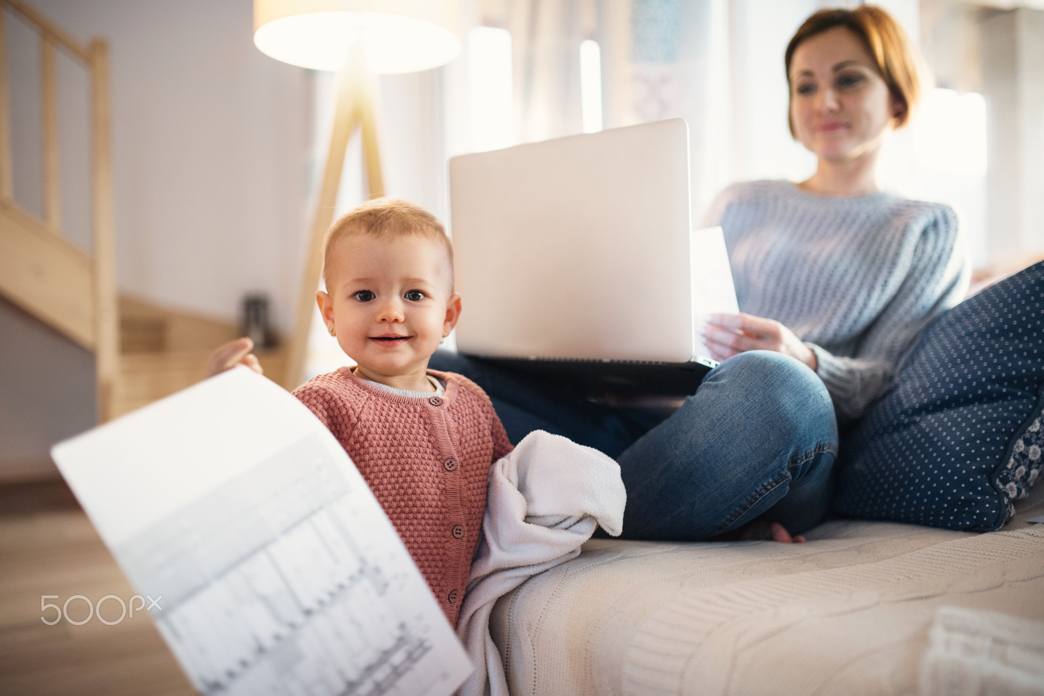 Young woman with a toddler daughter sitting indoors, working at home.